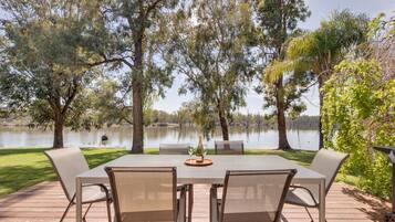 An outdoor dining area with a table and chairs, overlooking a lake.