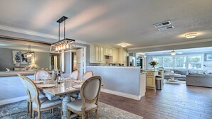 A spacious kitchen with a central island, wooden chairs, and pendant lighting.
