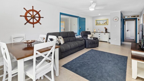 Un salon moderne comprenant un coin repas, un ventilateur de plafond, une grande fenêtre et une porte donnant sur une autre pièce.