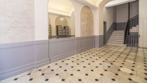 A spacious hallway with a patterned floor, a staircase, and arched doorways leading to another area. - Co-ownership (Nice)
