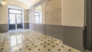 A hallway with a tiled floor, arched doorways, and a plain wall. - Co-ownership (Nice)