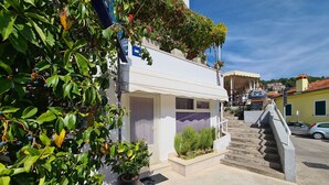 A building with a staircase leading to a covered entrance, surrounded by greenery and a clear sky. - Apartment 2127/39650 (Istria - Rabac), 200m from the beach (Rabac)