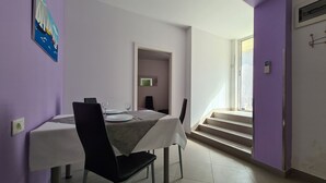 A dining area with a table set for two, a chair, and a staircase leading to an upper level. - Apartment 2127/39650 (Istria - Rabac), 200m from the beach (Rabac)
