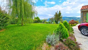 Un jardí ben cuidat amb diverses plantes i un camí de pedra que porta a un cotxe vermell.