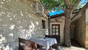 A stone building with a table and benches outside, a tree, and a door with frosted glass panels. - House 2134/45311 (Istria - Vidulini), 18000m from the beach (Vidulini)
