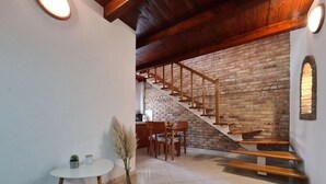 A dining area with a table and chairs, a staircase with wooden railings, and a brick wall. - House 2134/45311 (Istria - Vidulini), 18000m from the beach (Vidulini)