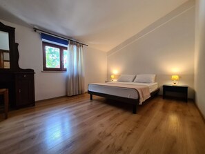 A bedroom with a bed, two bedside tables with lamps, a window with curtains, and a wooden dresser. - House 2134/45311 (Istria - Vidulini), 18000m from the beach (Vidulini)