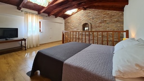 A bedroom with a wooden ceiling, a brick wall, a bed, a TV, and a window with curtains. - House 2134/45311 (Istria - Vidulini), 18000m from the beach (Vidulini)