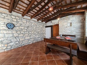 A rustic room with a stone wall, wooden beams, a dartboard, and a table with books. - House 2134/45311 (Istria - Vidulini), 18000m from the beach (Vidulini)