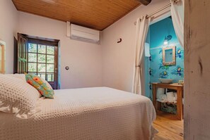 Relax in this serene bedroom with a comfortable bed, a large window, and a convenient bathroom nearby.