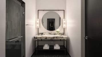 A modern bathroom with a large mirror, a marble sink, and a towel rack.