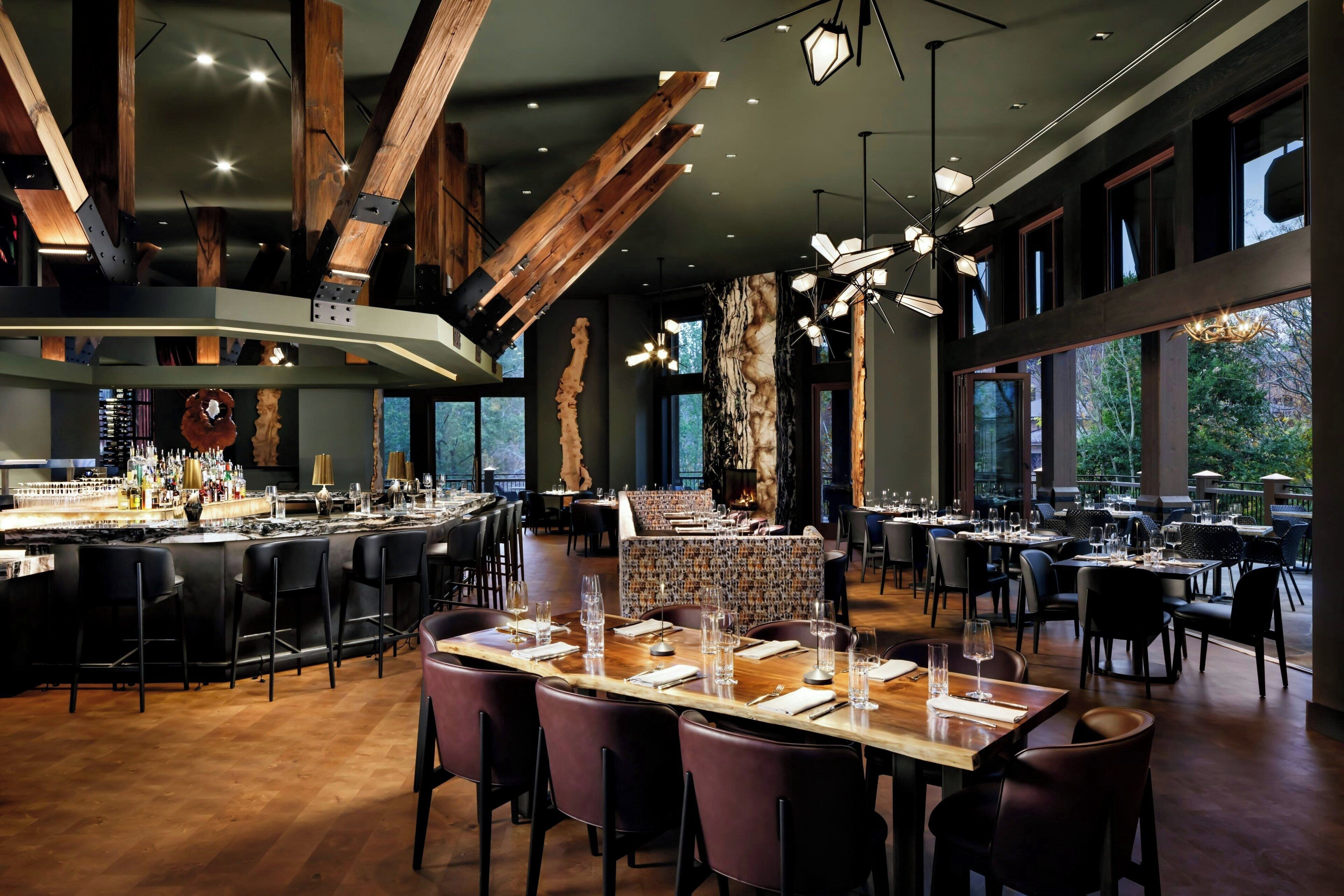 A modern restaurant with a bar area, high ceilings, and large windows.