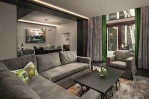 A modern living room with a grey sofa, a black coffee table, and a dining area with a table and chairs.