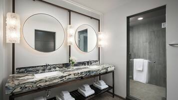 A modern bathroom with a marble sink, double mirrors, and a glass shower enclosure.