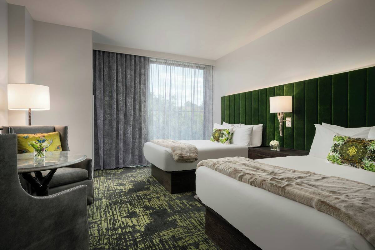 A hotel room with two beds, a desk, and a chair.