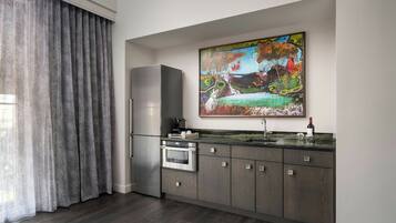 A modern kitchen with a stainless steel refrigerator, oven, and a marble countertop.