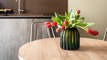A round wooden table with a vase of red tulips in the center, surrounded by metal chairs.