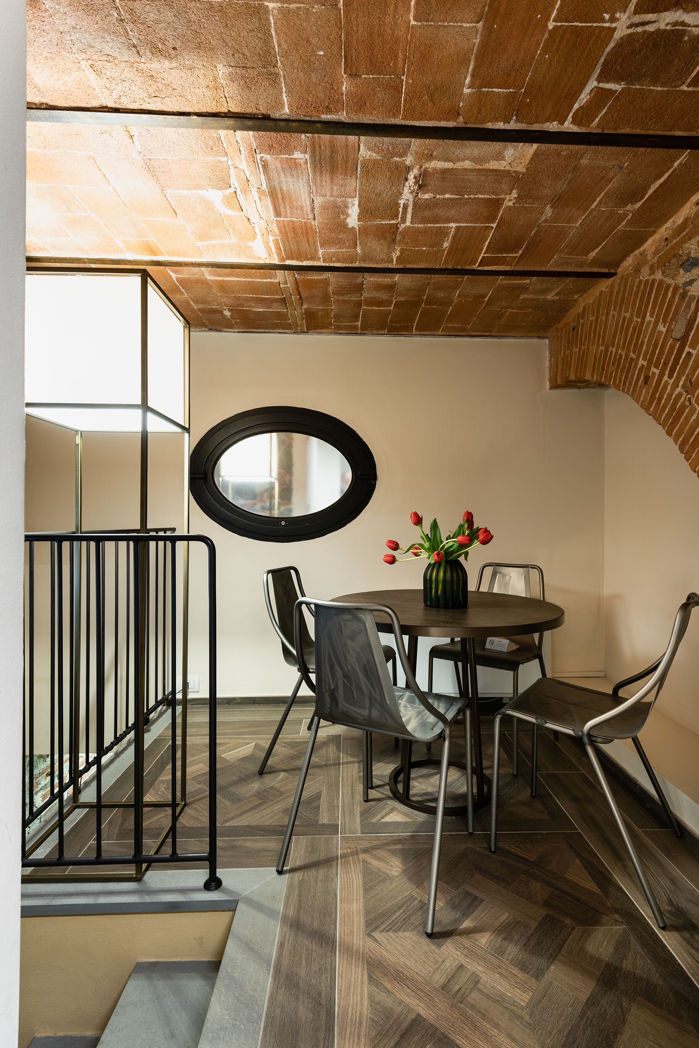 A modern dining area with a round table, chairs, and a vase of red tulips.