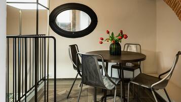 A modern dining area with a round table, chairs, and a vase of red tulips.