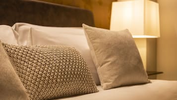 A sofa with patterned and plain cushions, a lamp, and a textured wall.