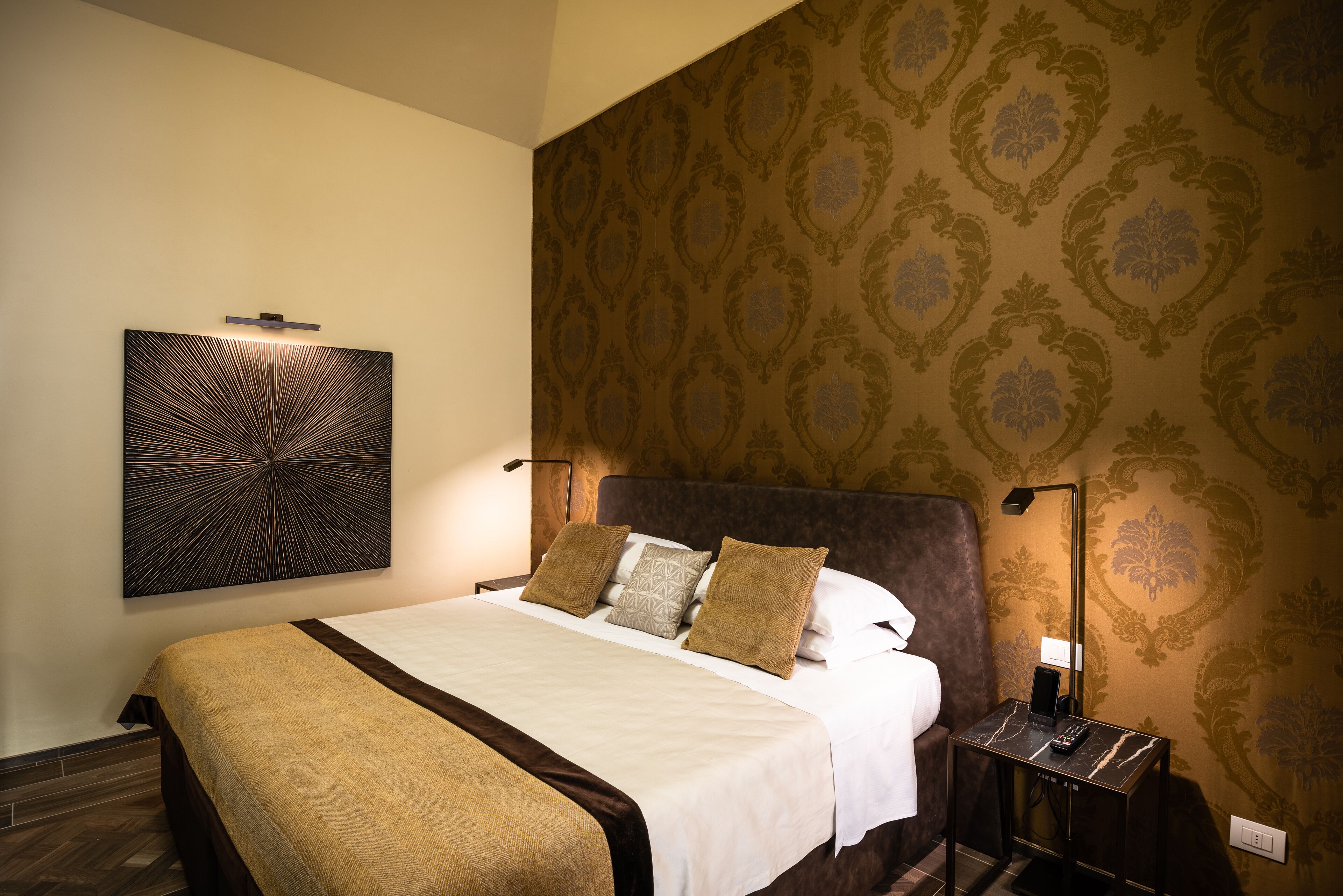 Une chambre d’hôtel avec un grand lit, une œuvre d’art accrochée au mur et un papier peint à motifs.