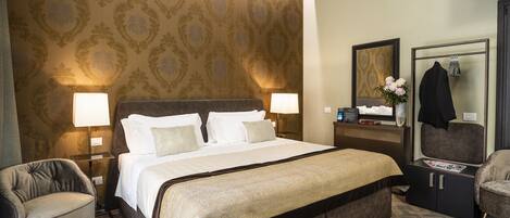 A hotel room with a large bed, two bedside lamps, a nightstand, a dresser, a chair, and a mirror.