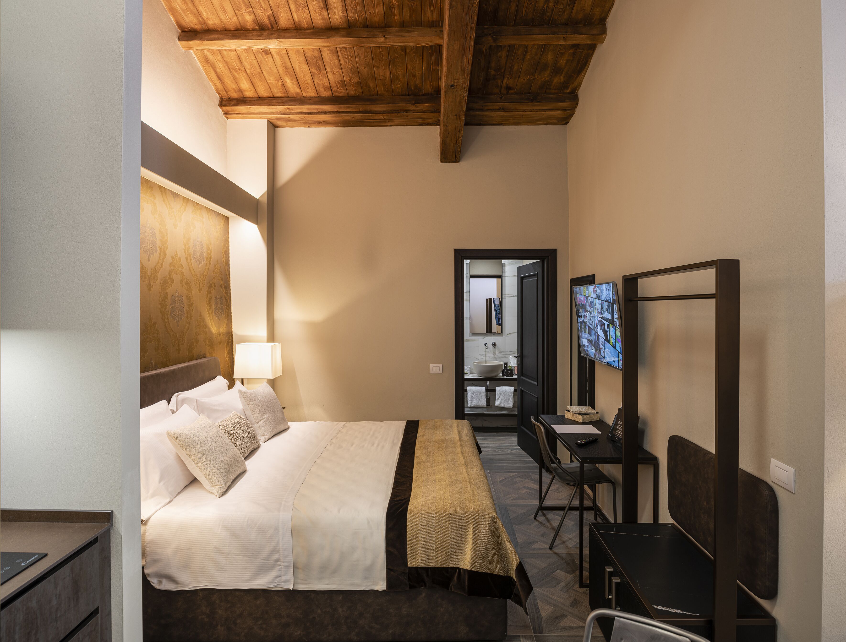 A hotel room with a bed, desk, chair, and a TV.