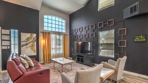 Ein modernes Wohnzimmer mit einem roten Sofa, beigen Sesseln, einem Couchtisch und einem Kamin.