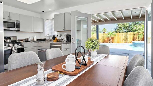 A modern kitchen with white cabinets, stainless steel appliances, and a dining area with a wooden table and chairs.