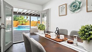 A dining area with a wooden table, chairs, and a view of a backyard with a pool.