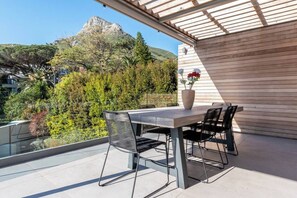 Eine Terrasse im Freien mit Tisch und Stühlen, einem Blumentopf und Blick auf einen Berg.