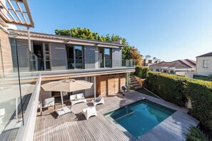 A modern house with a swimming pool, outdoor furniture, and a wooden deck.