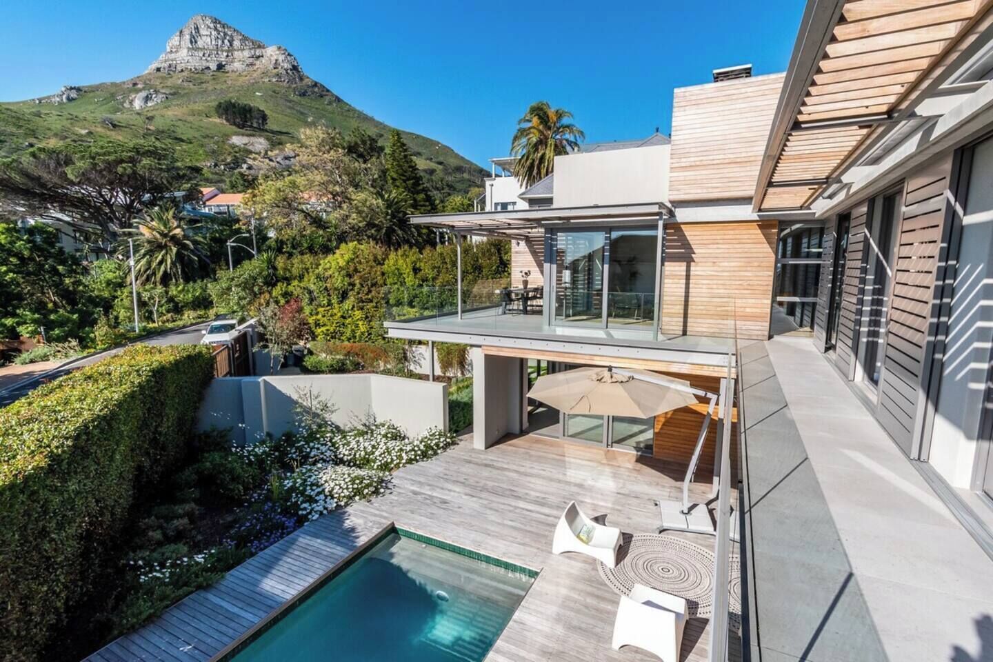 A modern house with a swimming pool, outdoor seating, and a view of a mountain.