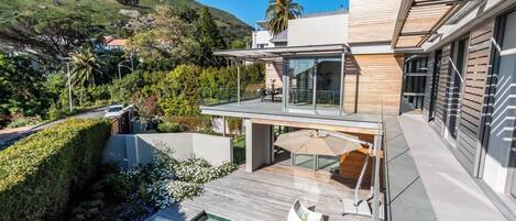 A modern house with a swimming pool, outdoor seating, and a view of a mountain.