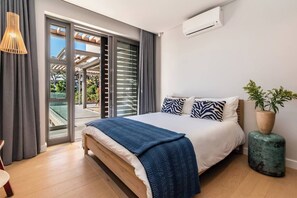Ein modernes Schlafzimmer mit einem Bett, einer Topfpflanze und Blick durch eine Glastür.