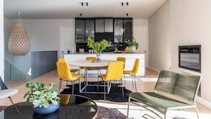 Uma sala de estar moderna com área de jantar, cozinha ao fundo e uma janela grande.