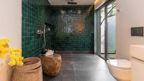 Casa de banho moderna com chuveiro, sanita e janela ampla.