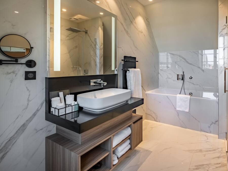 Un baño moderno con tocador de mármol, un espejo grande, una bañera y una ducha.