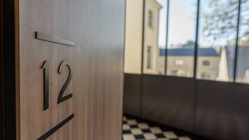 A wooden door with the number 12, a checkered floor, and a reflection of buildings outside.