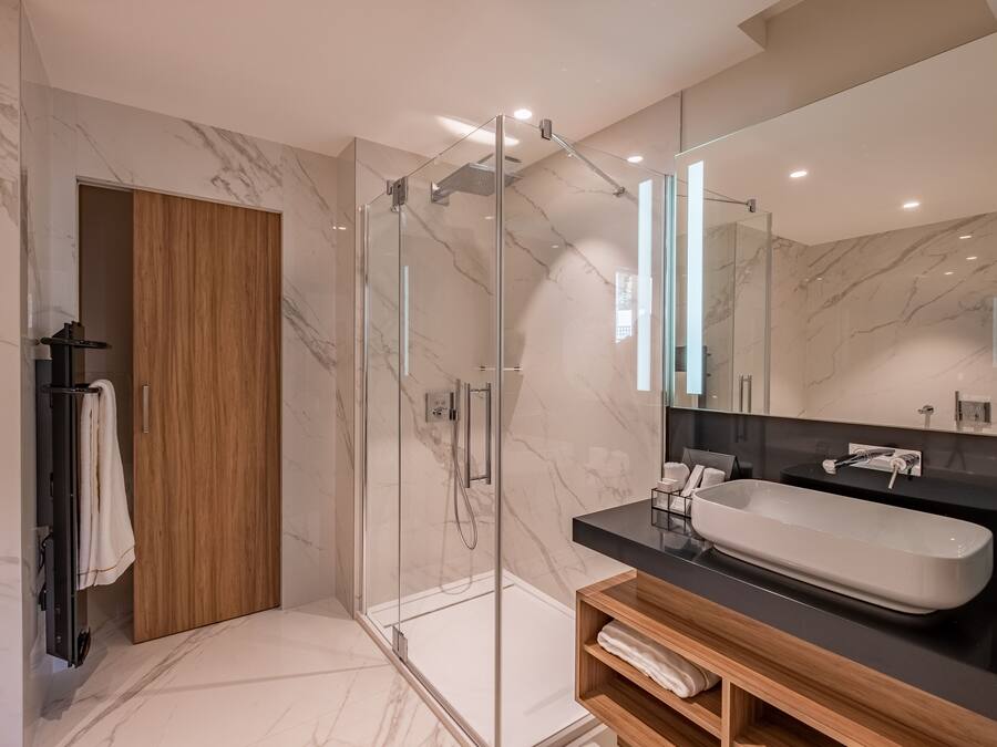 A modern bathroom with a glass-enclosed shower, a wooden vanity, and a large mirror.