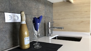Une cuisine moderne avec une bouteille de vin, deux verres à vin et un tapis noir sur le comptoir.