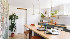 Une cuisine moderne dotée d’un îlot central, de luminaires suspendus et offrant une vue sur l’extérieur.