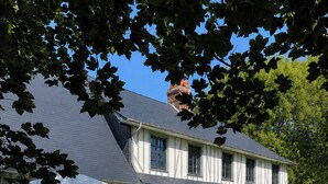 Une grande maison à deux étages, dotée d’un patio couvert et d’une pelouse.
