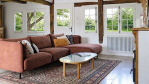 Un salon avec un canapé marron, une table basse en verre et un tapis à motifs.