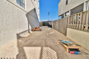 A narrow alley with a wooden fence, a picnic table, and a skateboard.