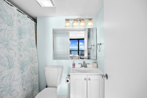 A bathroom with a toilet, sink, and mirror.