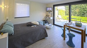 Een moderne slaapkamer met een bed, nachtkastje en een aan de muur bevestigde televisie.