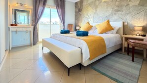 Un dormitorio con cama, mesita de noche, lámpara y vistas al exterior.