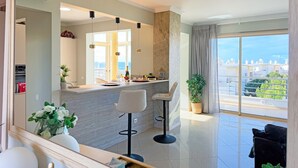 Una sala de estar moderna con un espejo grande, un comedor con barra y un balcón con vistas.