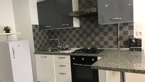 A modern kitchen with a granite countertop, white cabinetry, a built-in oven, and a stainless steel sink. - Superb Mont Carlo Hamam Sousse vacation apartment (Hammam Sousse)